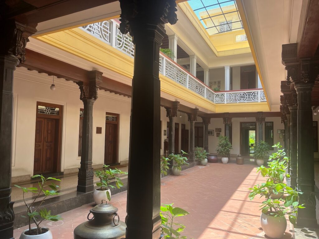 The heart of Chettinad hospitality — Visalam’s sun-drenched open courtyard, ringed by polished pillars and rooms, where gatherings, rituals, and quiet moments still unfold under
the gaze of ancestral portraits.